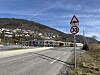 Fartsgrenseskilt på 30 km/t ved vegkant med bygningar og fjell.